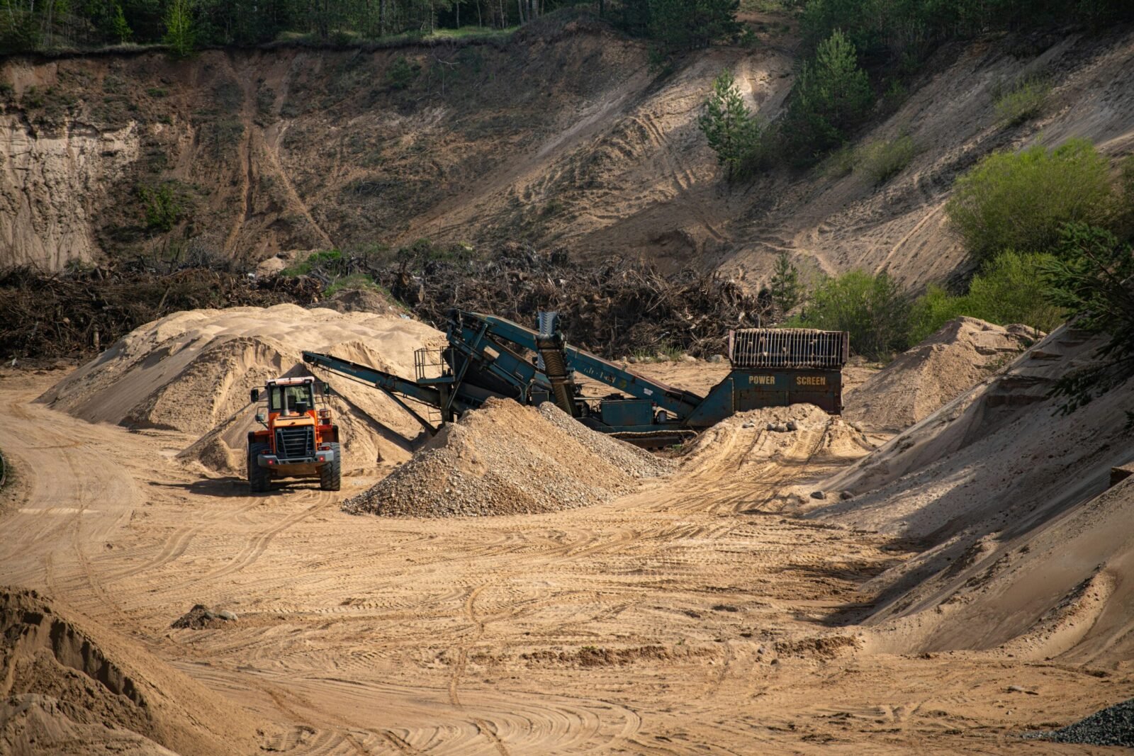 A sand quarry in Lithuania with heavy machinery, showcasing industrial landscape and construction activity.